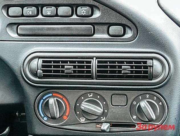 Chevrolet Niva Кнопка кондиционера так и просится на место заглушки в климатическом блоке, но по каким-то причинам стоит наверху. Магнитола здесь «внешняя».