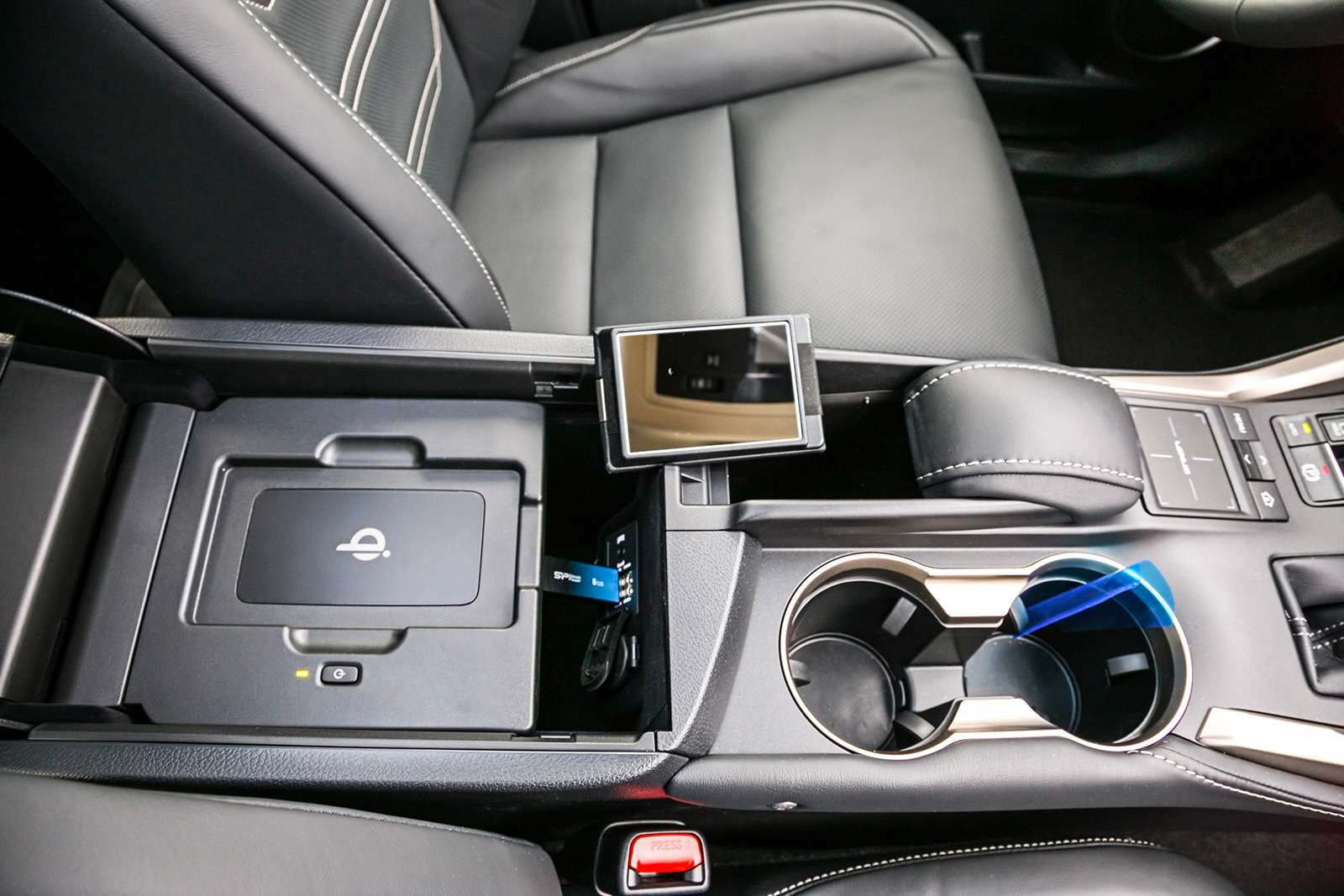 А вот и то самое «лишнее» зеркальце! Под крышкой центрального бокса Lexus NX 300h помимо мультимедийных слотов есть местечко для беспроводной зарядки смартфона