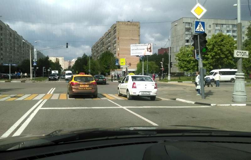 Перекресток Юбилейного проспекта и улицы Южной в городе Реутов Московской области. Если водитель желтого такси продолжит движение строго по прямой, то окажется на встречной полосе. Чтобы благополучно миновать перекресток, ему необходимо сместиться правее, но должен ли он при этом уступить дорогу коллеге справа?